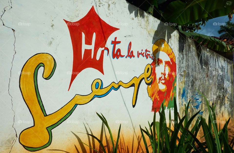 Vinales, Cuba - December 21, 2013: Colourful painting of Cuban revolutionary commander Che Guevara and slogan Hasta La Victoria Siempre on the wall on the outskirts of Vinales, Cub at sunset time