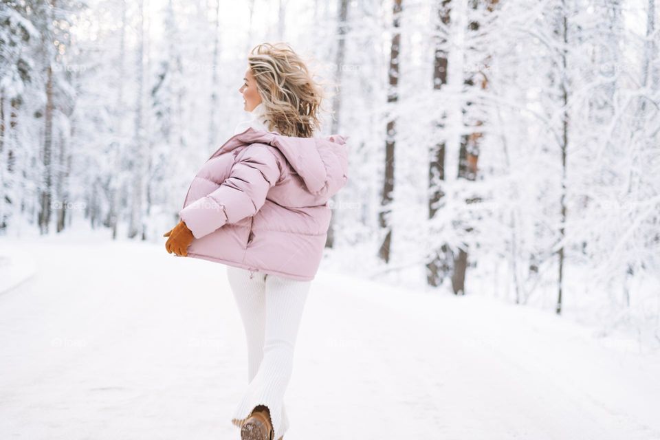 Blurred blonde woman in winter clothes in snowy winter forest