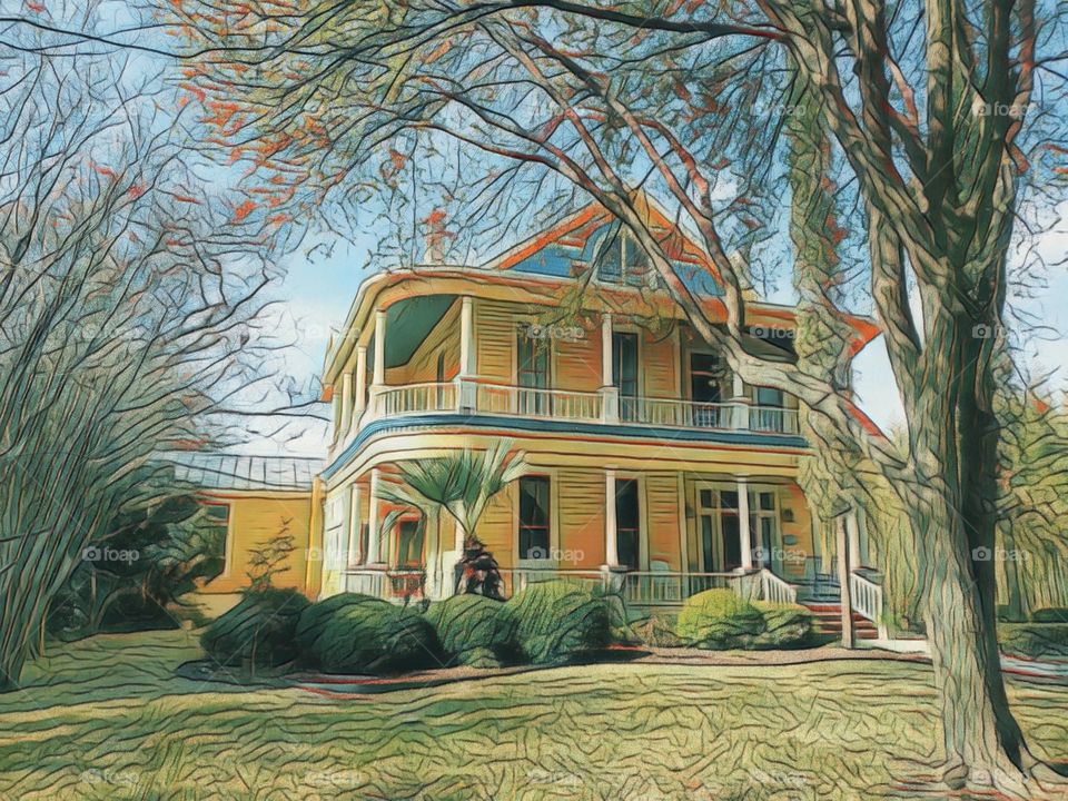 Colorful two story yellow home from the 1800s with a wrap around second floor porch.