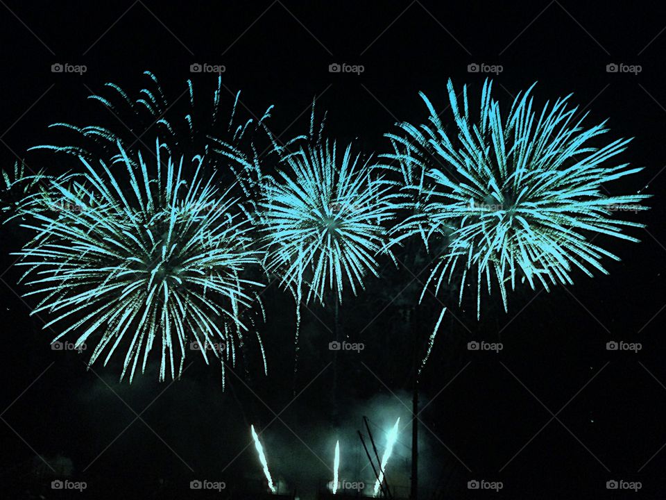 Three dazzling blue fireworks explode into the night sky.