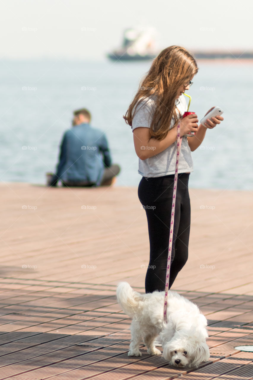 Young Girl With Her Dog Using Mobile Phone Outside