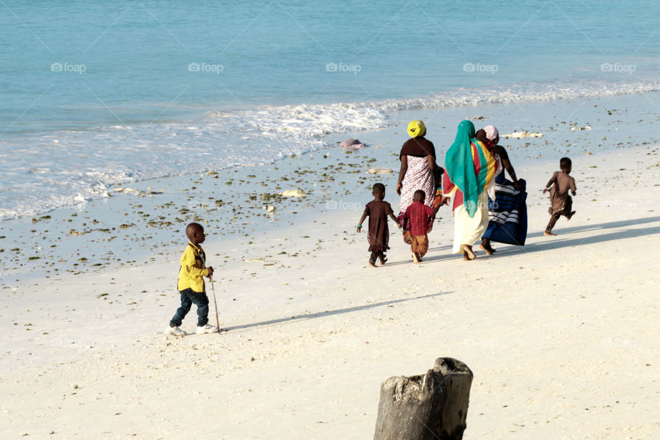 Islanders. Local people walking on the white sands of beautiful Zanzibar. 