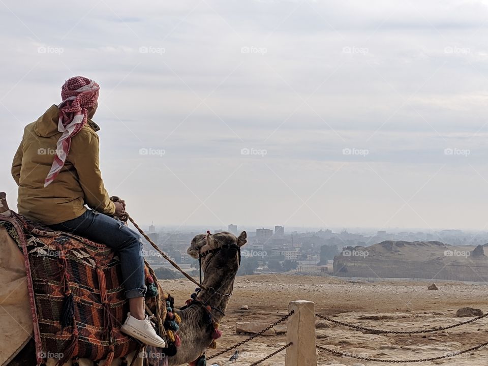 Man riding a camel by the pyramids, over looking Giza and Cairo, Egypt
