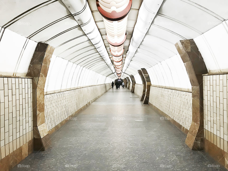 People walking through the subway tunnel with geometric pattern 