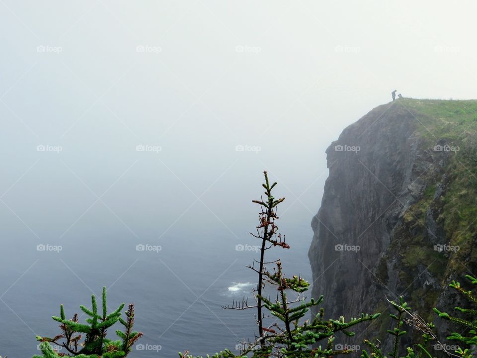 Man proposing to woman atop a misty cliff along the beautiful coast of Newfound and Labrador.  Hard to tell but I think she said yes!