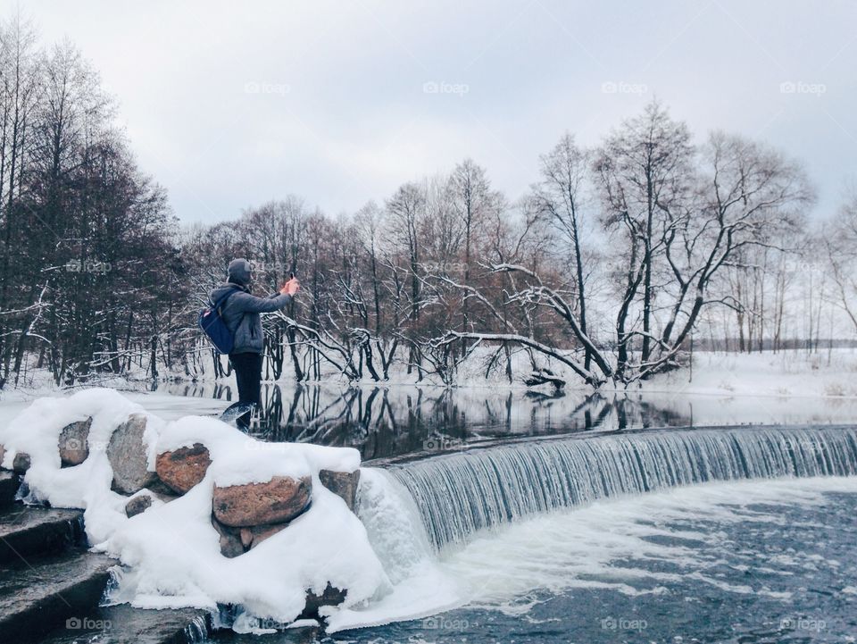 A person taking picture of waterfall