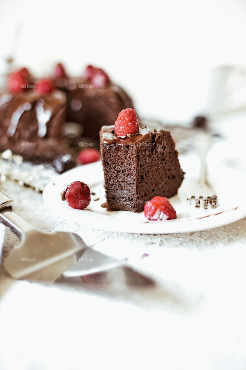 a piece of chocolate cake with chocolate topping and strawberry, brownie