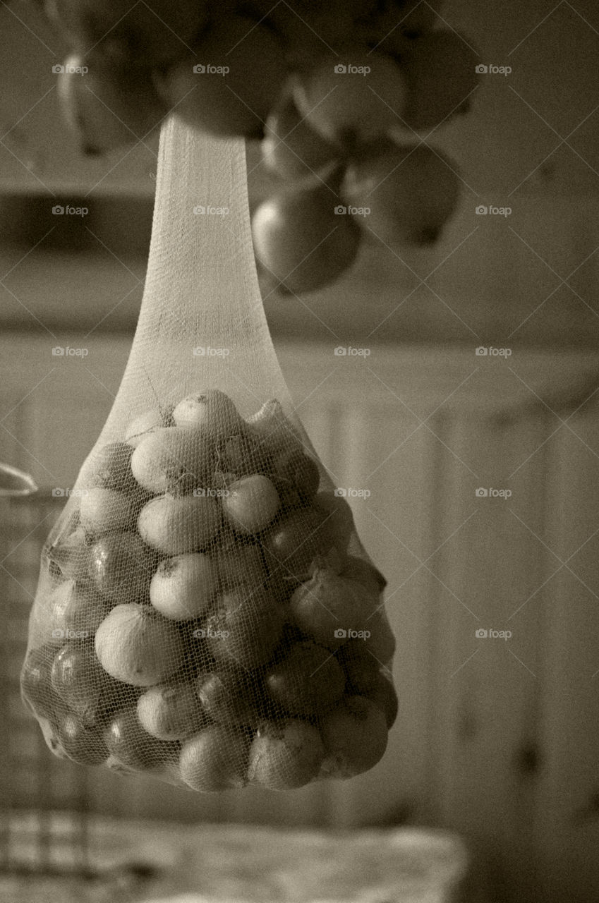 Ripe onion in bag hanging under the stairs