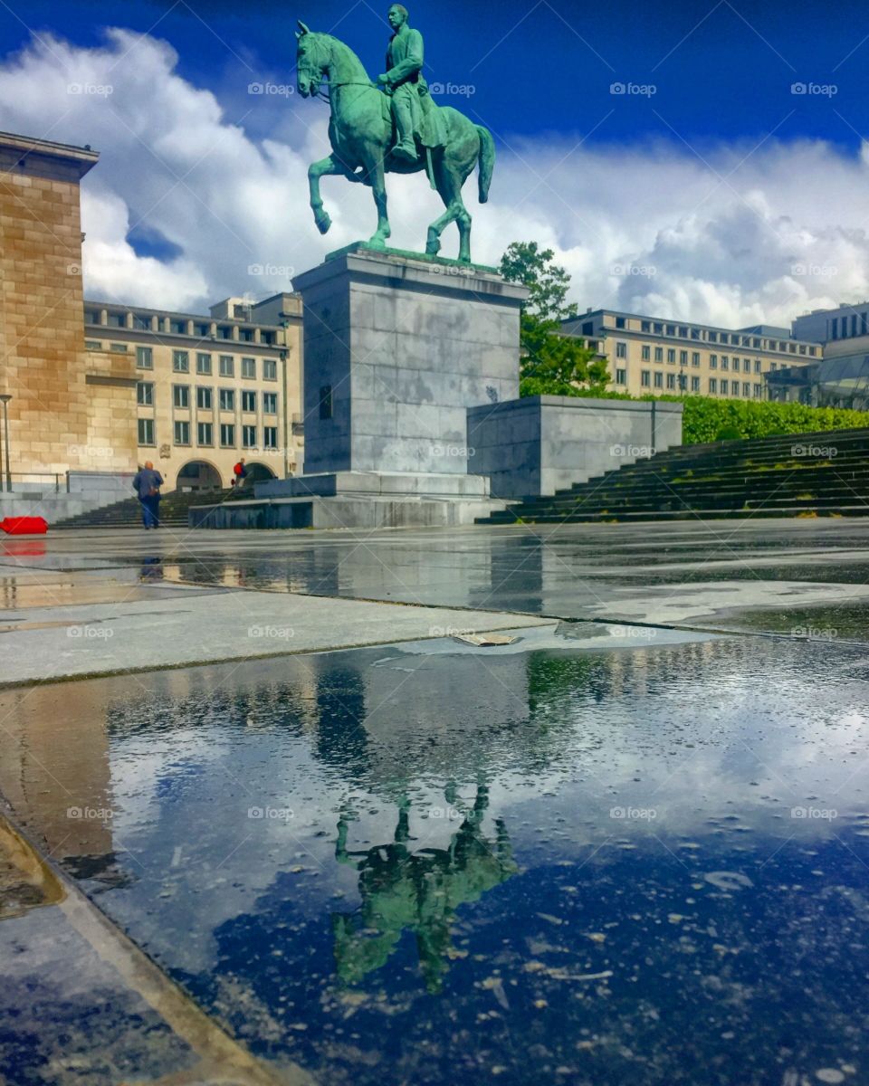 Reflected horseman statue in a puddle after the rain in Brussels city