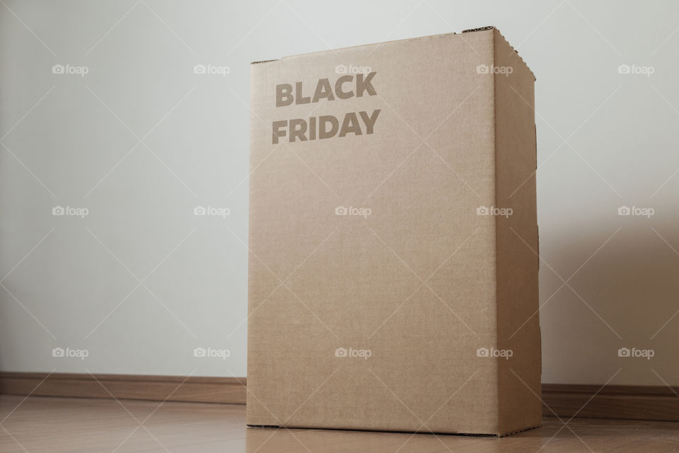 Cardboard box with black friday order written on the box placed on the floor in an empty room with a neutral background. delivery concept. economy concept. black friday concept. shopping concept.