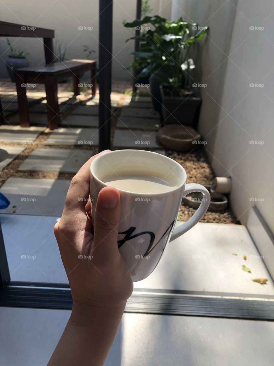 Sitting in the sun with a cup of coffee, with a beautiful view of the garden. 