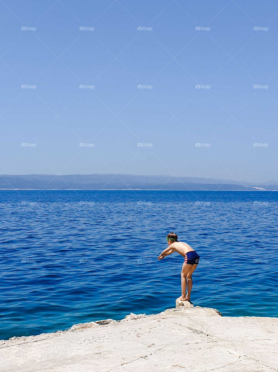 Boy preparing to jump from the parapet into the sea.  Summer vacation at sea.  Croatia, Brela