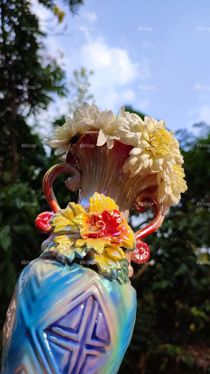 Beautiful white flowers in a colourful flowerpot with a flower sculpture