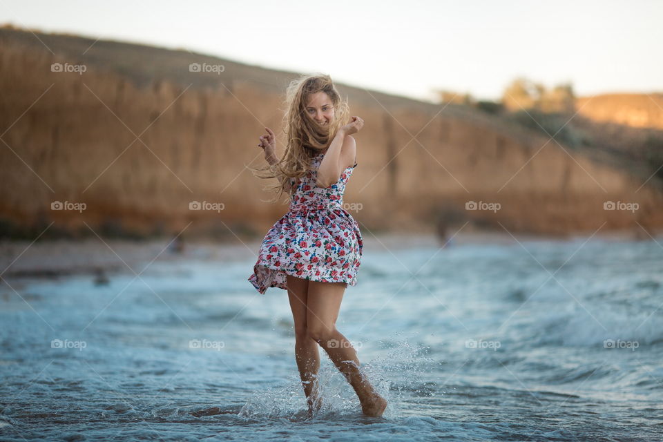 Portrait of beautiful young woman near the sea at sunset