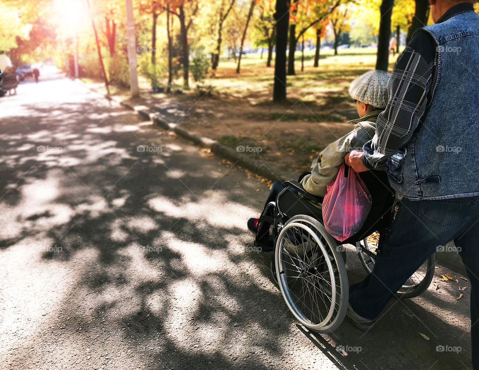 Woman in wheelchair under the shadow of the trees 