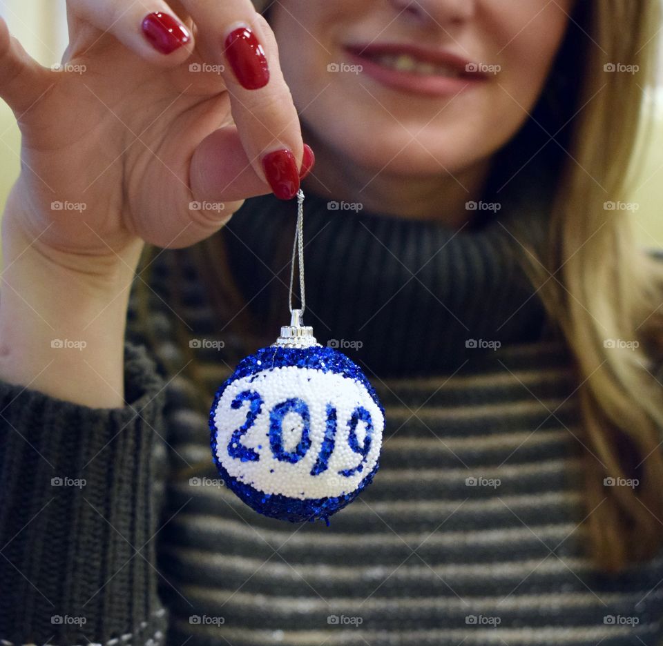 The girl is holding a New Year's toy with the inscription 2019