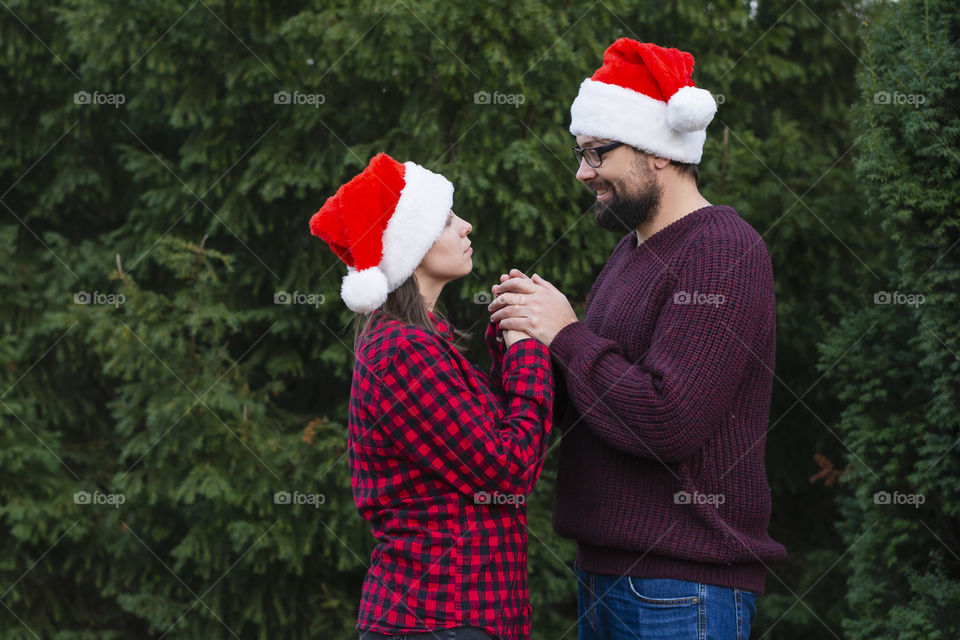 Loving couple in a cozy sweater and shirt against of Christmas trees on the street, a man warms the hands of a woman. Concept: winter holidays weekend with family winter forest Black Friday
