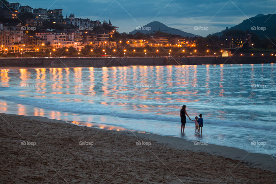 Woman standing on beach with her children atdusk