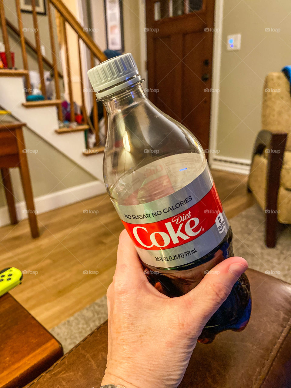 Have a a coke and a smile...bottle of Diet Coke being held by a woman while watching tv in her living room.  Simple shot, hand in frame. 