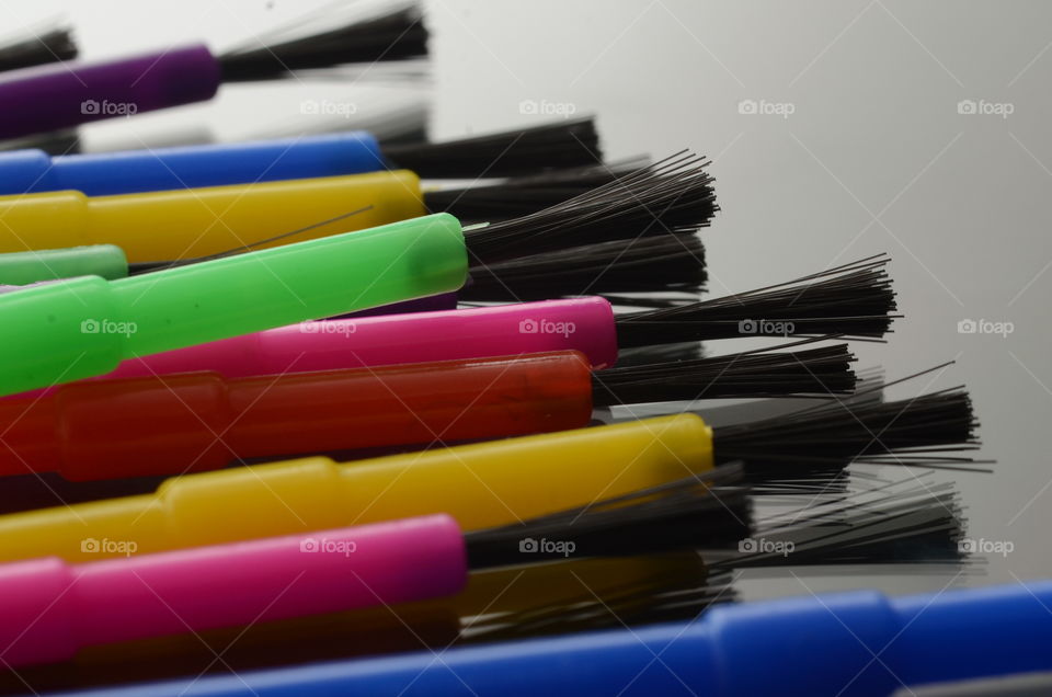 Paint brushes lying on a computer laptop come in a rainbow assortment of colors.