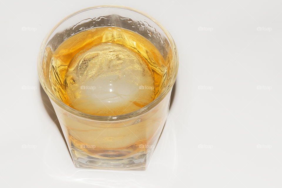 A glass of whiskey with a large round ice ball