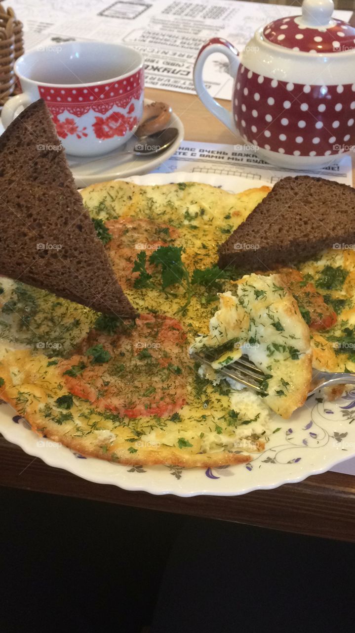 Egg omelet with tomato and cheese with dark bread on plate