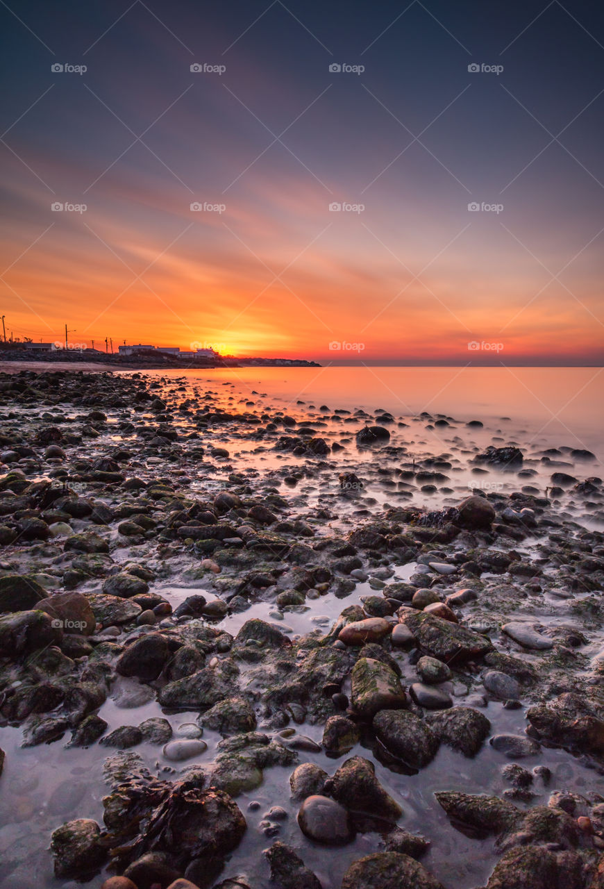 Orange sunset over a rocky beach