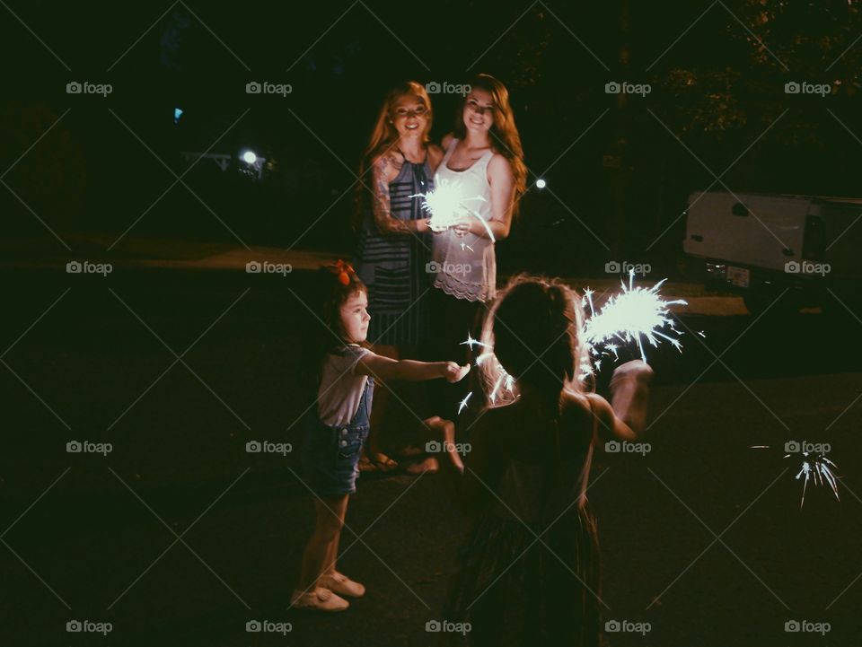 Two women with their children lighting fire crackers