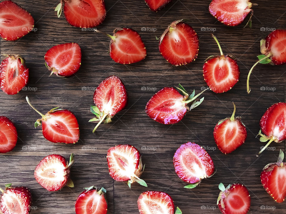 Slices of red ripe strawberries on wooden background 