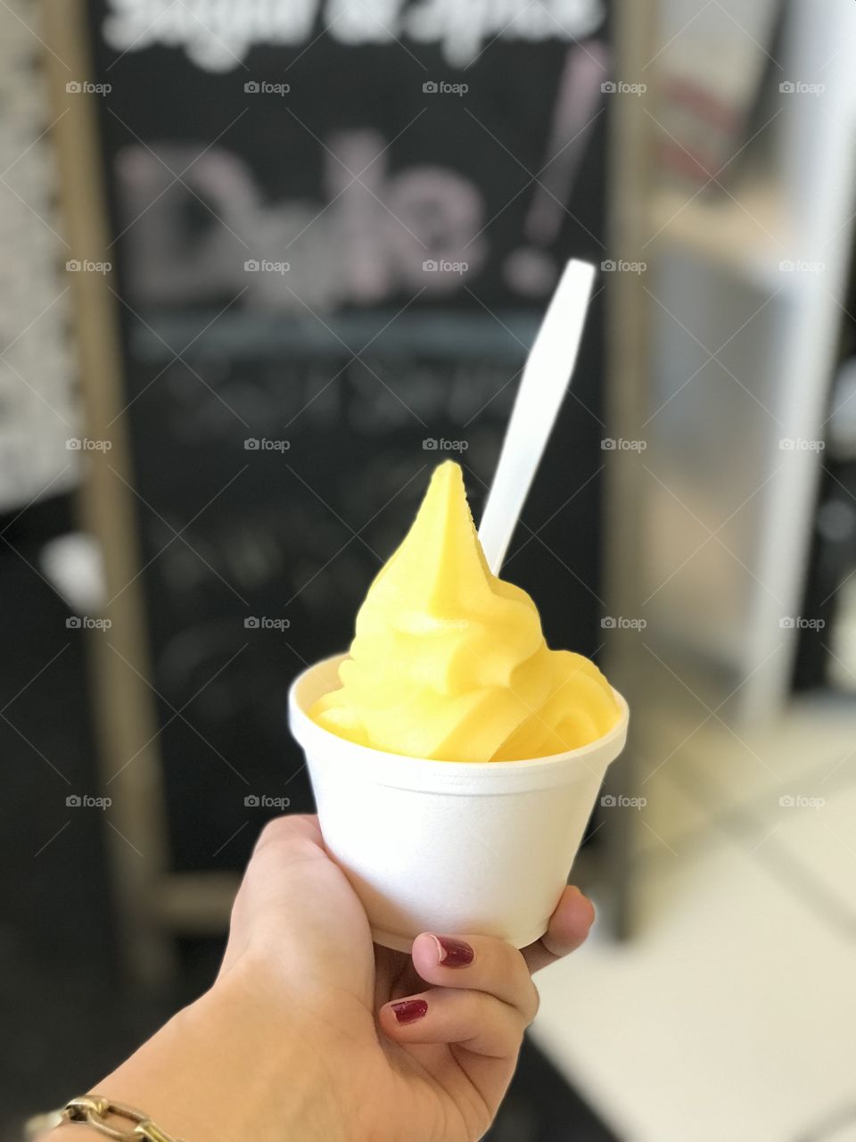 Hand holding pineapple dole whip in cup