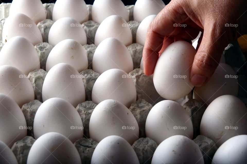 hand picking an egg. hand picking an egg from an egg tray