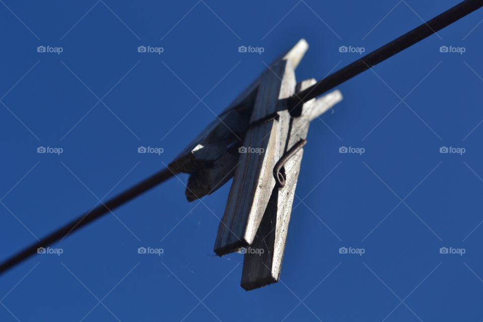 Old wooden clothespins clothespins in clothesline against a vivid indigo blue sky stark contrast 