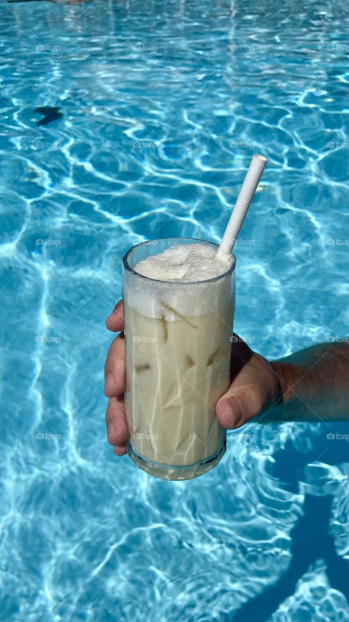 Having a cold drink in the swimming pool on a hot sunny day in summer 
