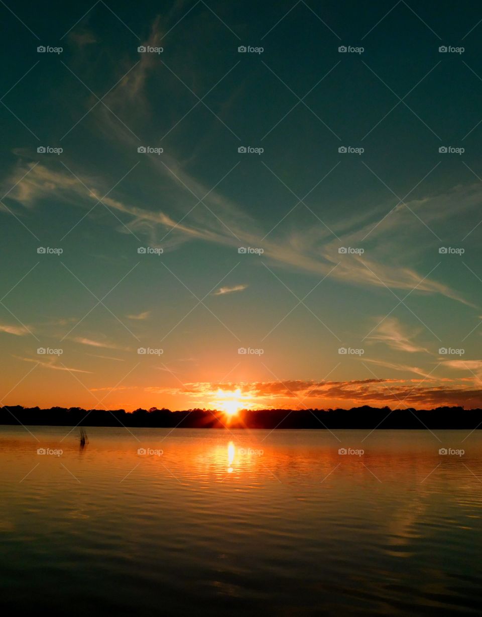 Reflection of sunlight on lake during sunset