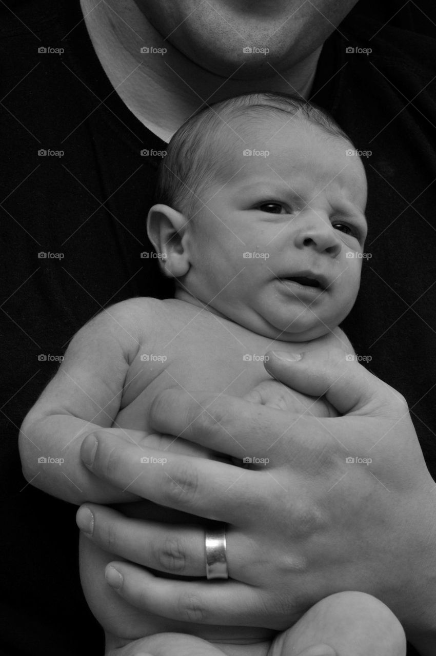 Newborn parents, tiny, baby boy, in his father’s arms, black, and white portrait