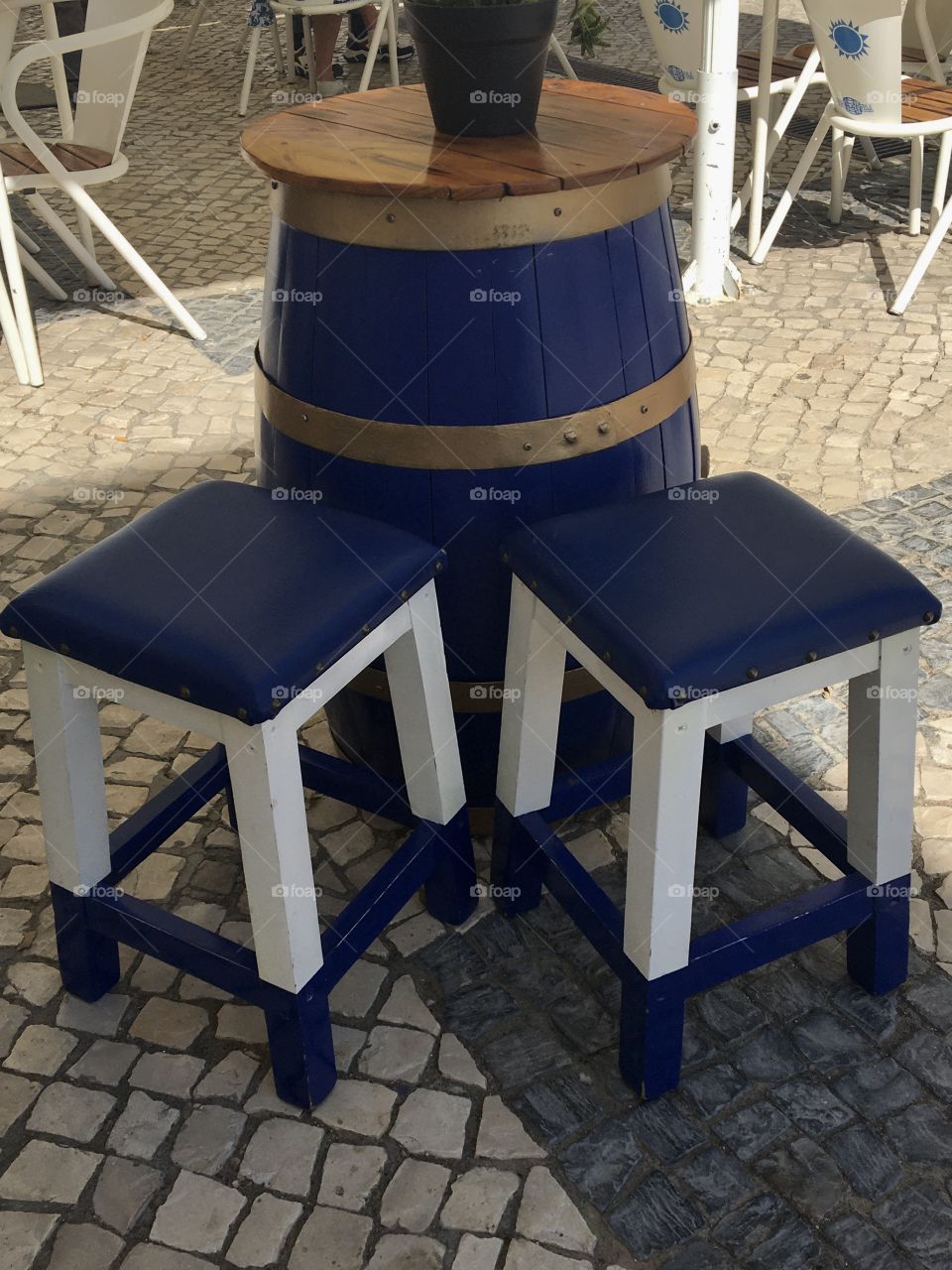 One blue barrel and 2 stools on traditional pavement
