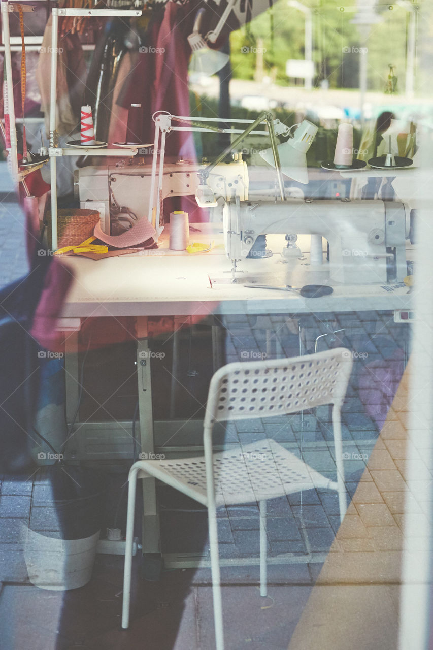 Workplace of dressmaker using sewing machine and various sewing related items. Candid people, real moments, authentic situations