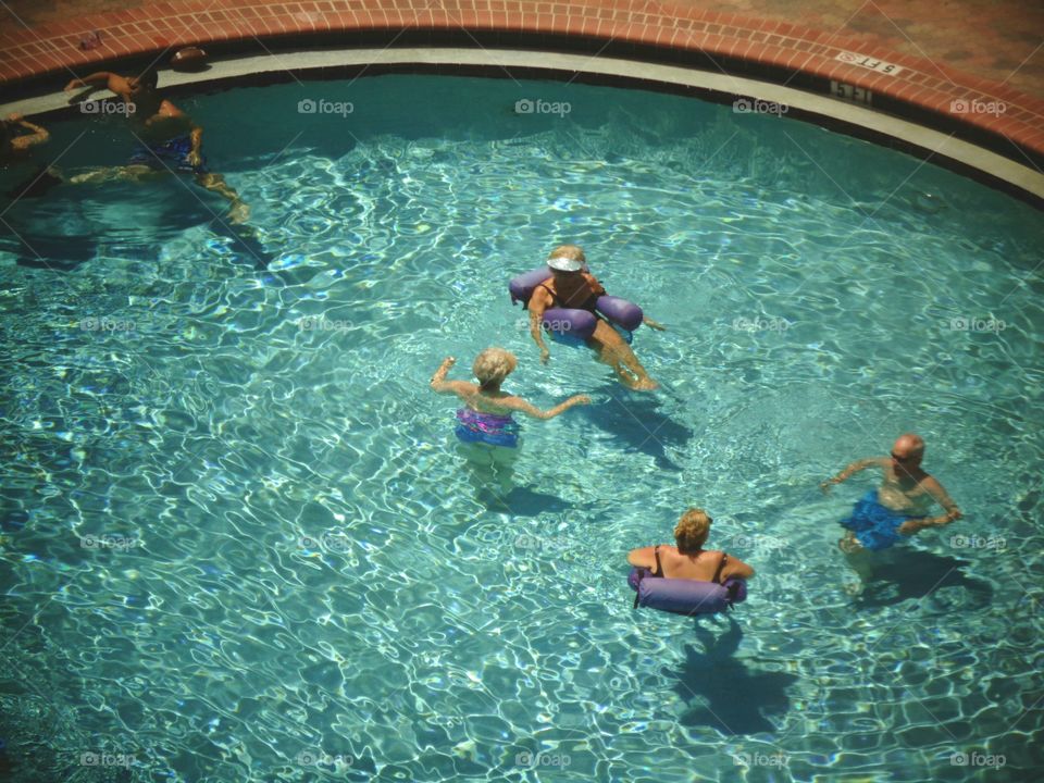 Round swimming pool, from above. People enjoying the water.