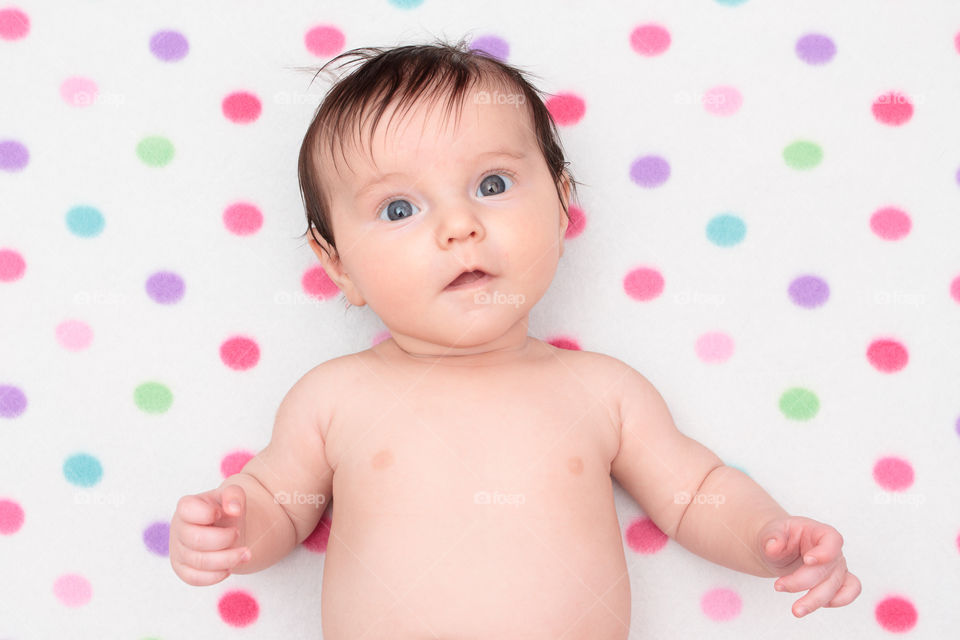 Little baby lying on a blanket. Little baby girl lying on blanket with colourful polka dots