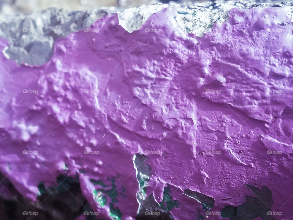 close up of detailed granite wall in an old building painted with purple color