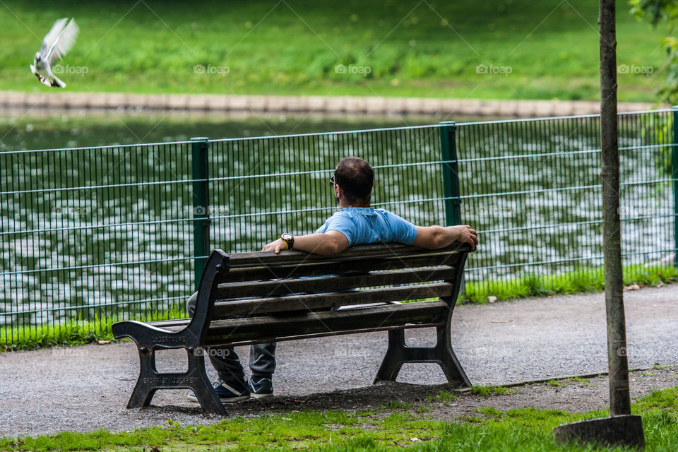 Man relaxing while sitting on the city park bench