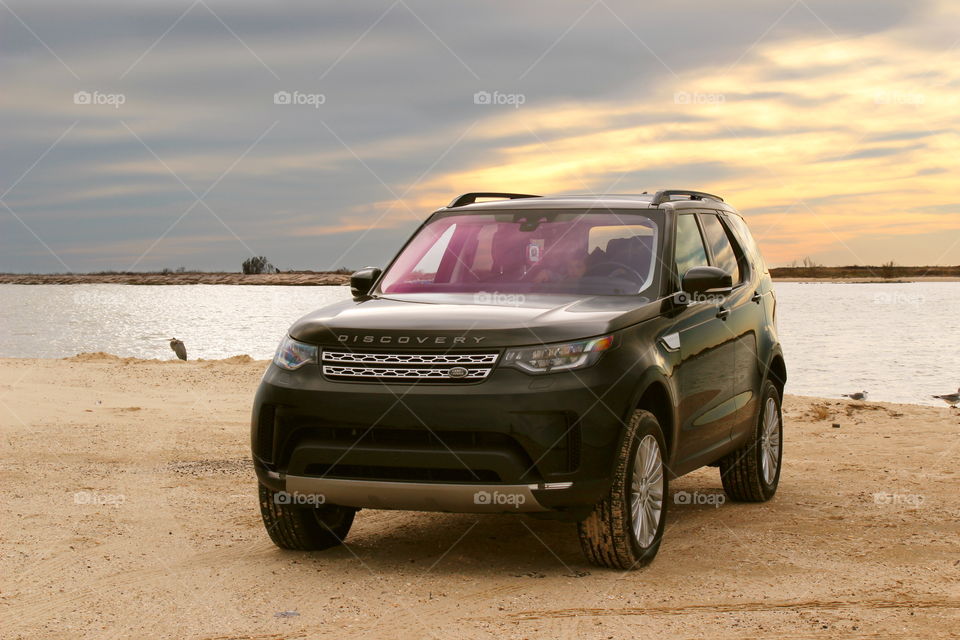 Black 2017 land rover discovery offroad on beach at sunset with sand, water, seabird. Jetty park, matagorda, texas