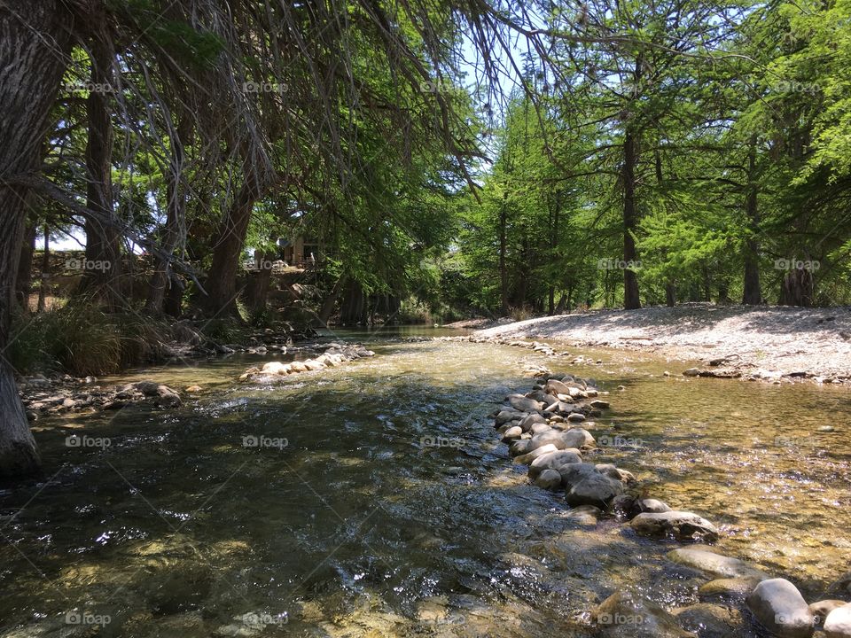 A tranquil walk through a rocky area of shallow, gentle, clear water rapids in the Frio River in Leakey, TX. 