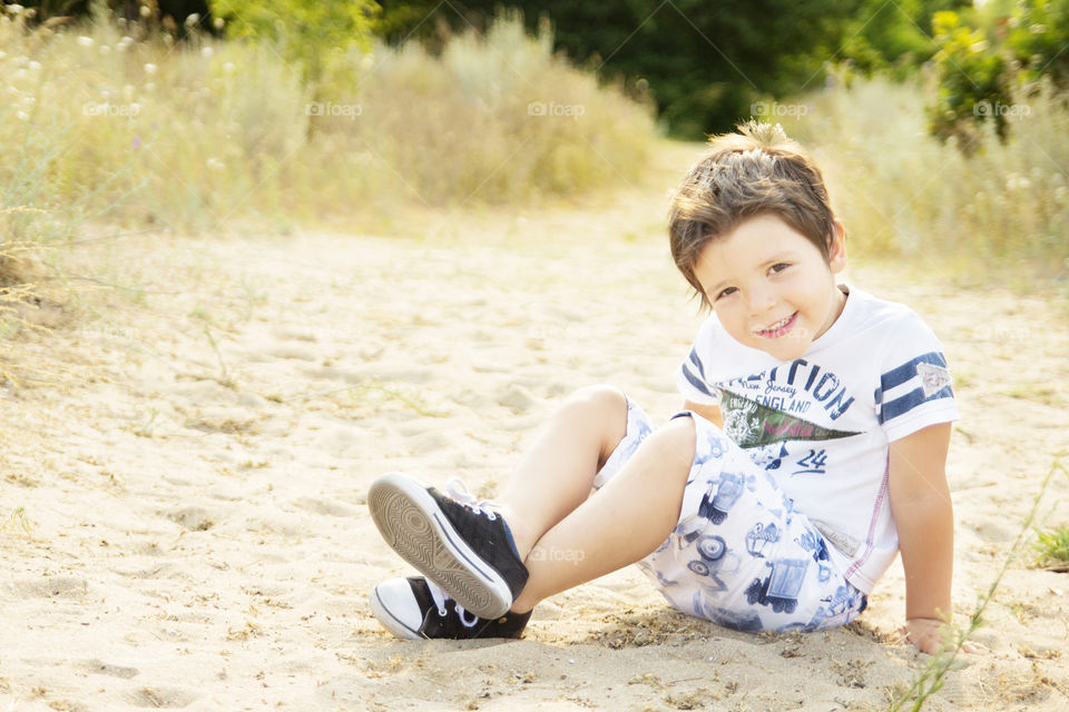 boy sitting on the beach. smiling boy sitting on the sand