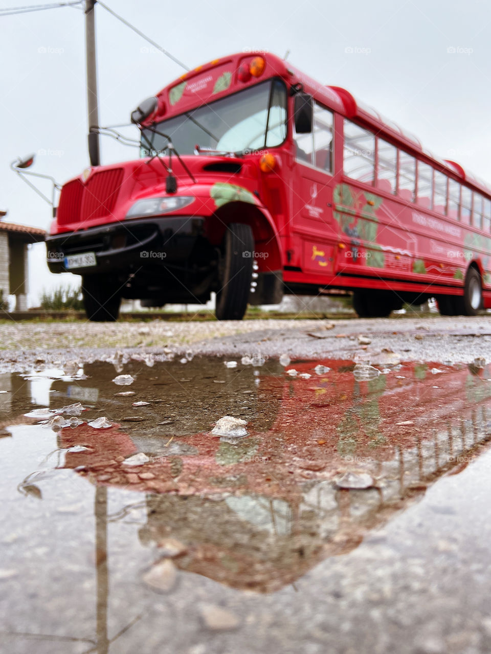 Image of a large red tourist bus reflected in a puddle in winter. Travel conception. Slovenia.
