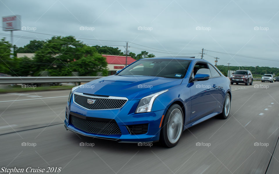 2017 vector Blue Cadillac ATS-V cruising down the interstate in Houston, cloudy skies
