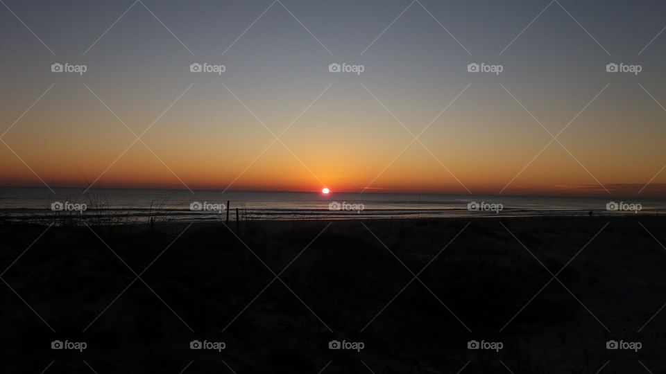 I captured this photo of the sunrise on the Atlantic Ocean in Jacksonville Beach Florida. Notice the sun rising out of the ocean. Check out the orange glow in the Eastern skies.