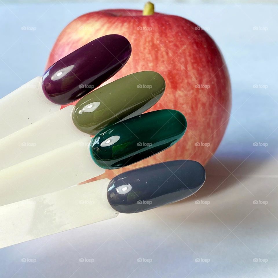 Palette of autumn colors of nail polish on an apple background. 
