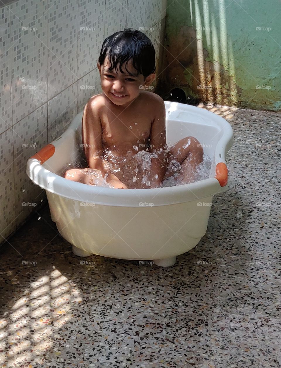 happy kid enjoying his bath in tub in summer