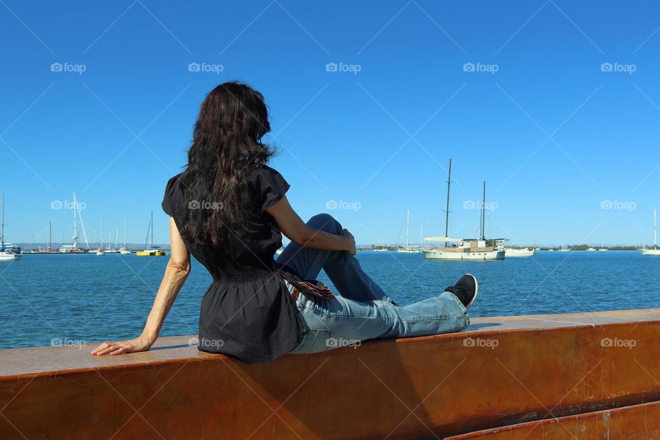 A seated girl looks at the ocean